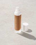open bottle of Fenty Beauty Pro Filt'r Soft Matte Longwear Foundation with pump dispenser in shade 385 on concrete background