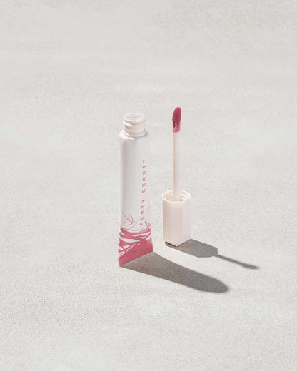 Open tube of Pro Kiss'r Luscious Lip Balm in shade Pinch Me on grey background.