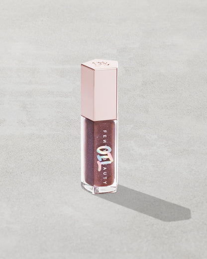 Gloss Bomb Oil Luminizing Oil and Gloss in shade Rose Amber product against a concrete background.