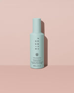 The Water Boi Reparative Leave-In Conditioner Spray on a peach background.