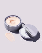 Instant Reset Gel container opened next to its lid, showing the applicator, on a lilac background.